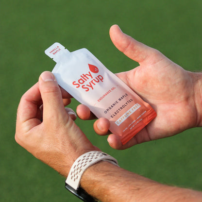 Athlete holding Salty Syrup OG gel packet on turf field