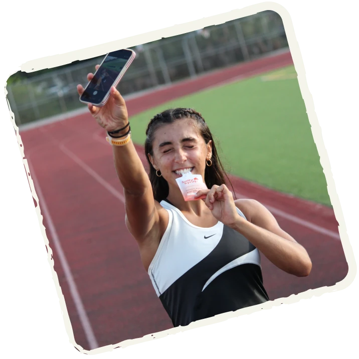 Runner holding up a Salty Syrup packet on the track